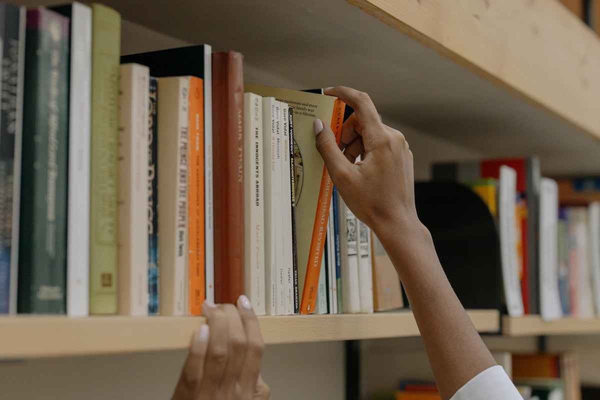 Estudiante eligiendo un libro de una estantería.