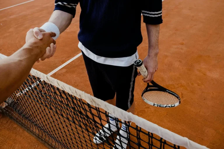 Tennis players shaking hands over tennis net