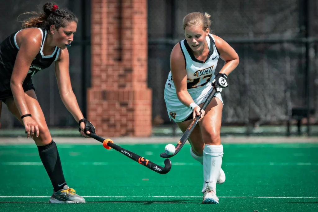 Two female field hockey players competing for the ball during a match.