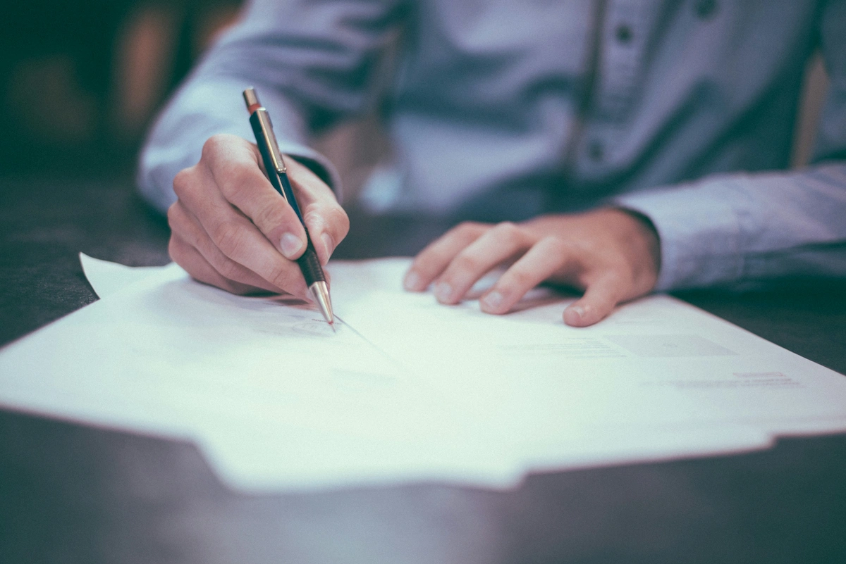 Male student signing paperwork at a desk