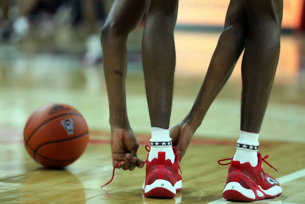 A basketball player ties his shoes.